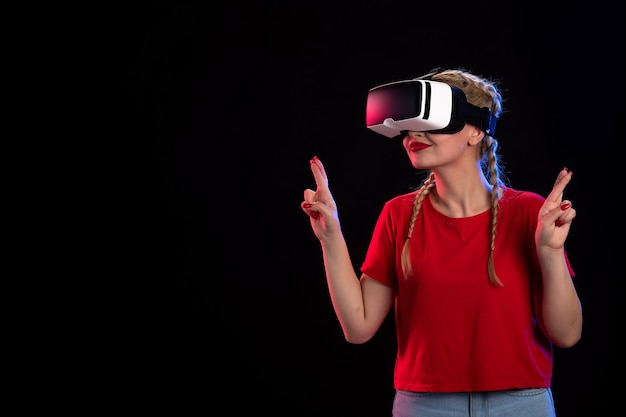 Front view of young female playing vr on dark wall