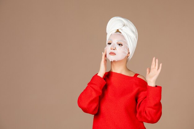 front view young female preparing to apply face mask on pink background