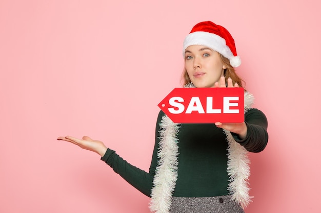 Free photo front view of young female in red cap holding sale writing on pink wall