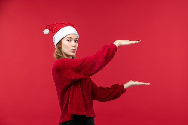 Front view young female in red cap showing size on red desk red woman holiday