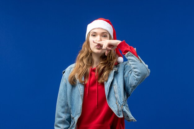 Front view young female in red christmas cap posing on blue background christmas emotion color