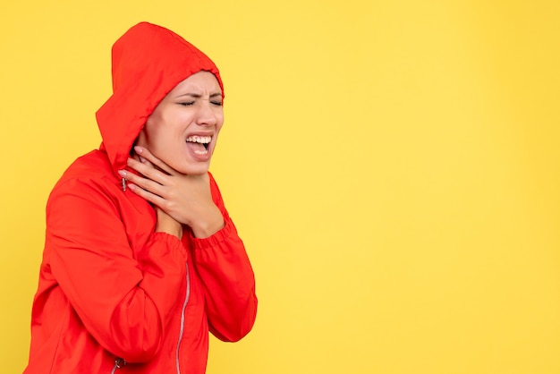 Front view young female in red coat having sore throat on yellow background