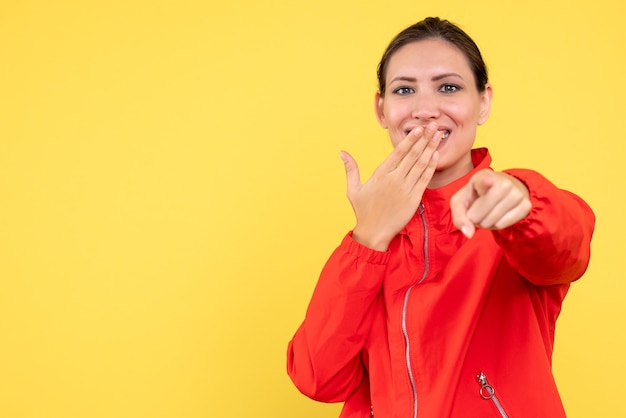 Front view young female in red coat laughing on yellow background