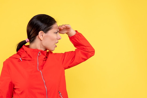 Front view young female in red coat looking on yellow background