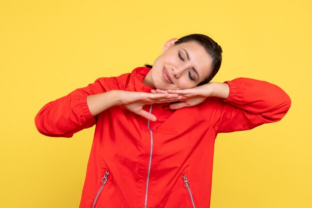 Front view young female in red coat sleeping on yellow background