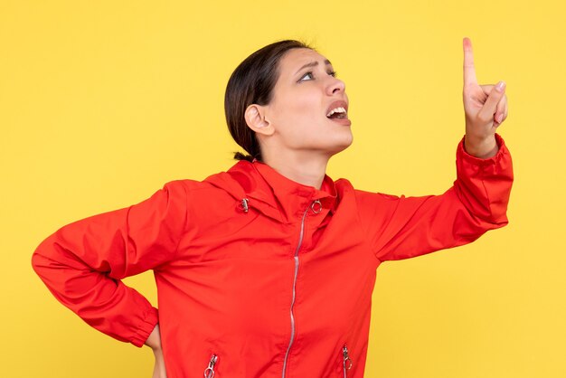 Front view young female in red coat on a yellow background