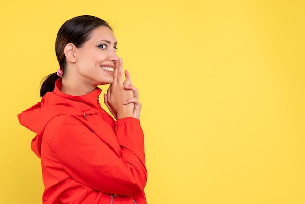 Front view young female in red coat on a yellow background