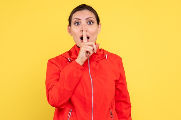 Front view young female in red coat on yellow background