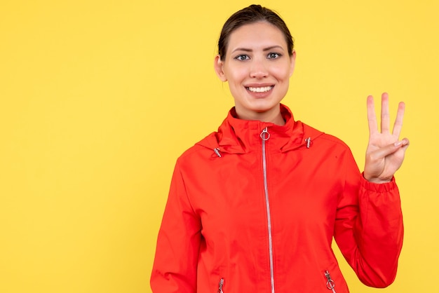 Front view young female in red coat on yellow background