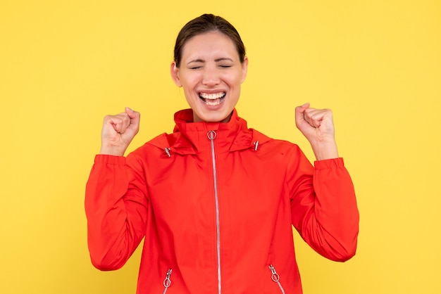 Front view young female in red coat on yellow background