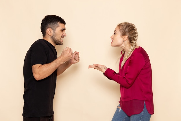 Free photo front view young female in red shirt quarelling with young man on the cream space female cloth  quarell