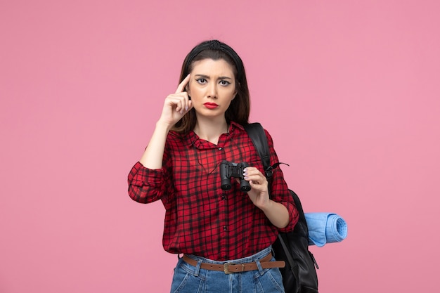 Front view young female in red shirt with binoculars on a pink background student color woman