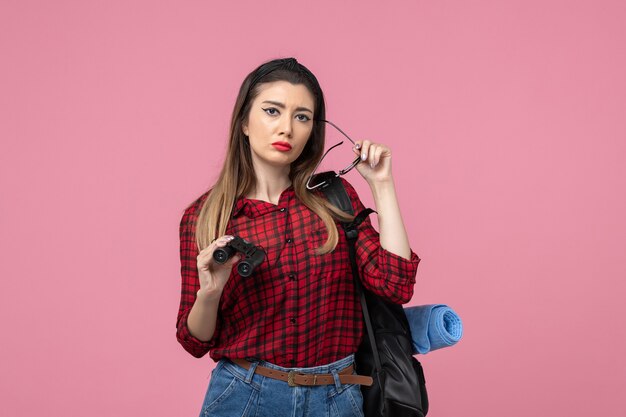 Front view young female in red shirt with binoculars on pink background woman colors model