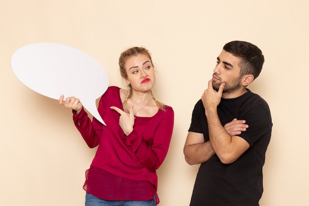 Free photo front view young female in red shirt with male holding white sign on the cream space female cloth  photo