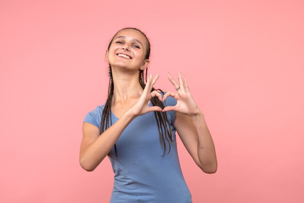 Front view of young female sending love on pink