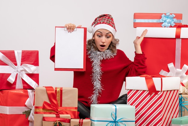 Free photo front view young female sitting around christmas presents with note