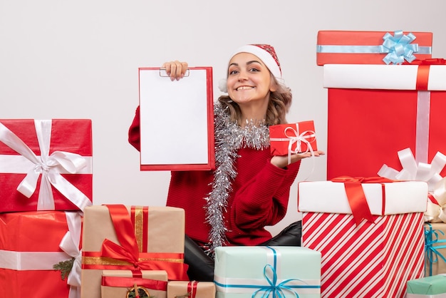 Front view young female sitting around christmas presents with note