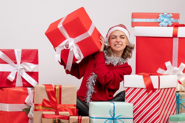 Front view young female sitting around christmas presents