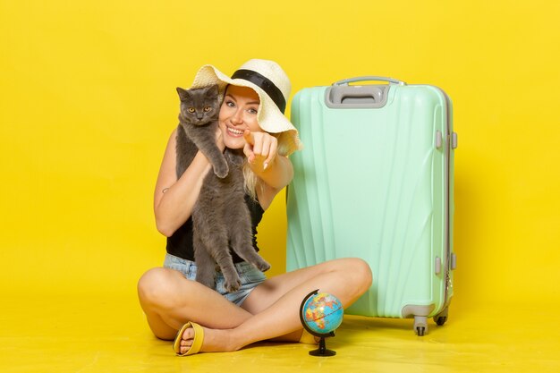 Front view young female sitting and hugging kitten on yellow wall trip vacation voyage sea journey sun