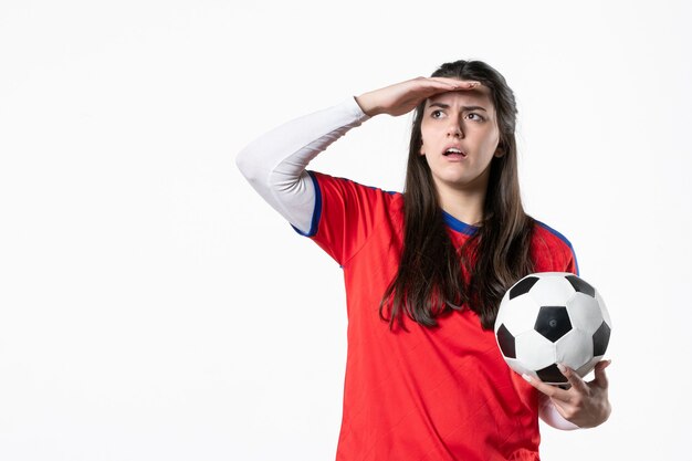 Front view young female in sport clothes with soccer ball on white wall