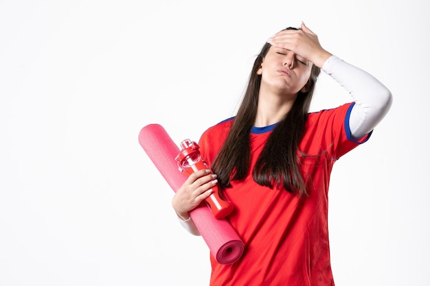 Front view young female in sport clothes with yoga mat on white wall