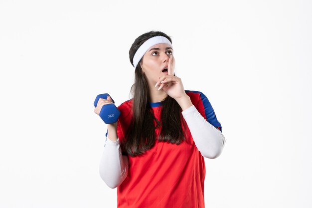 Front view young female in sport clothes working out with dumbbells on white wall