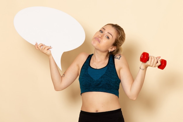 Front view young female in sport outfit holding dumbbells and white speech bubble