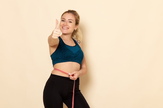 Front view young female in sport outfit measuring her body with smile