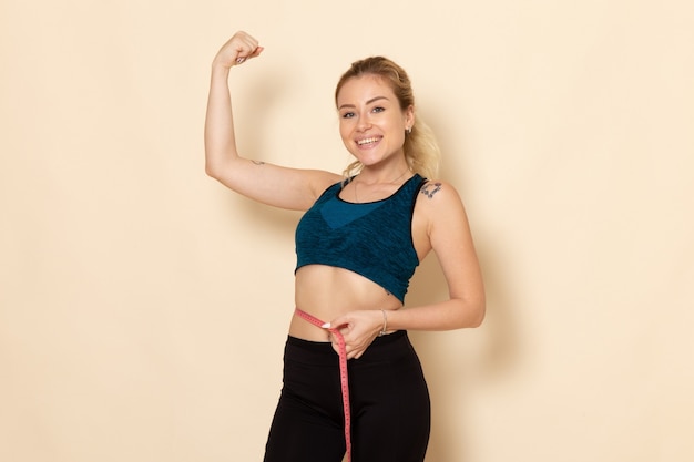 Front view young female in sport outfit measuring her sizes and waist