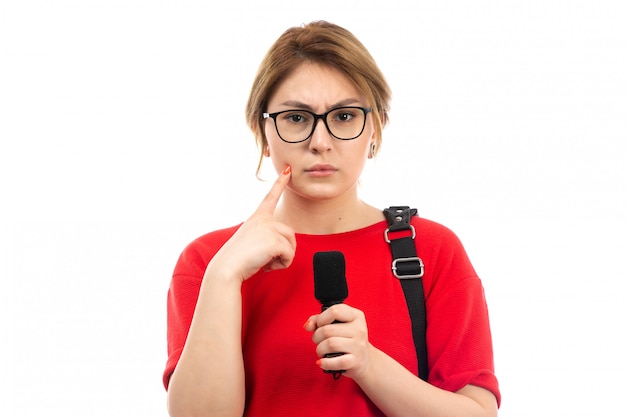 Free Photo a front view young female student in red t-shirt wearing black bag holding microphone hesitating expression on the white