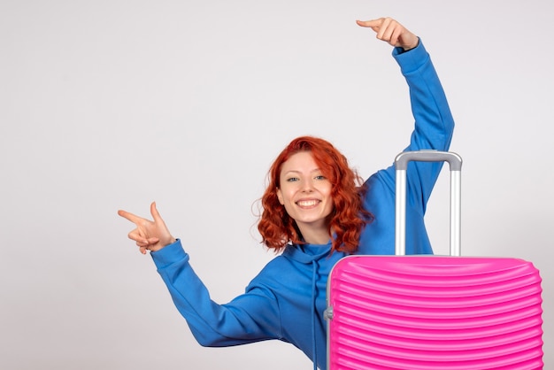 Front view of young female tourist with pink bag on a white wall