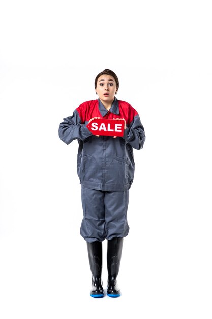 front view young female in uniform holding red sale nameplate on white background