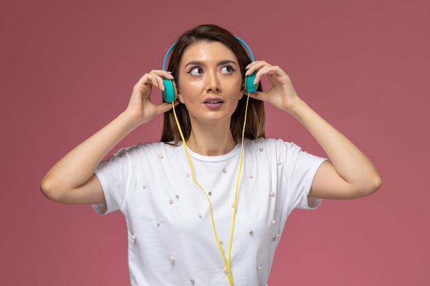 Free photo front view young female in white shirt posing and listening to music on the pink wall, color woman model