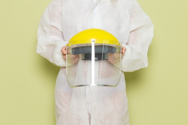 Free photo front view young female in white special suit and yellow helmet holding it on the green space