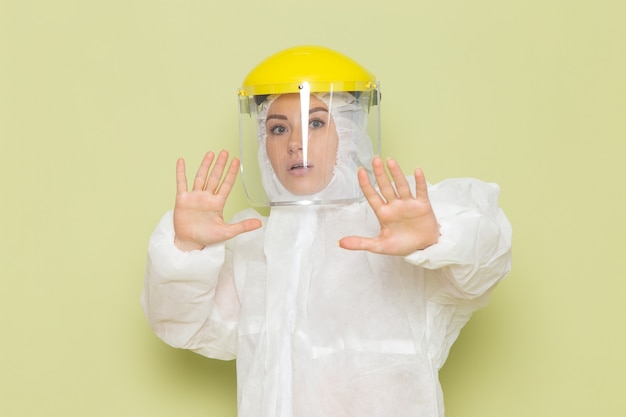 Front view young female in white special suit and yellow helmet posing with caution on the green space suit uniform science