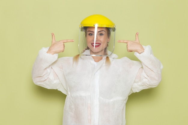 Free photo front view young female in white special suit and yellow helmet smiling on the green space job