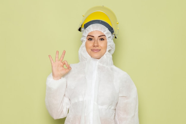 Free Photo front view young female in white special suit and yellow helmet smiling showing alright sign on the green space job 