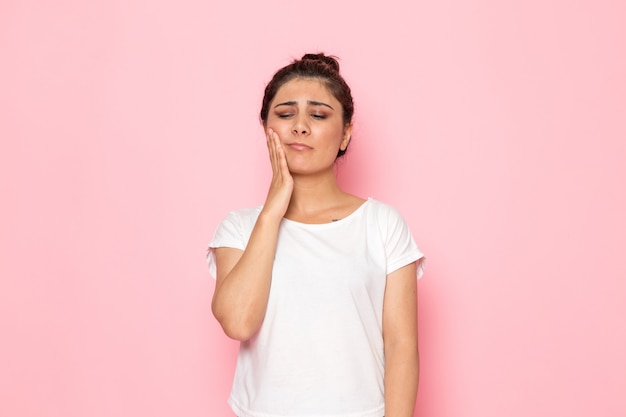 A front view young female in white t-shirt and blue jeans having a toothache