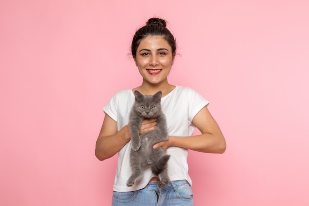 Free Photo a front view young female in white t-shirt and blue jeans holding grey kitten