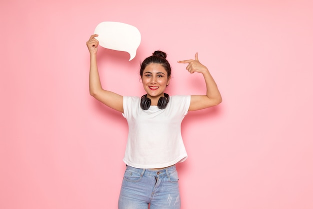 A front view young female in white t-shirt and blue jeans holding white sign with smile on her face