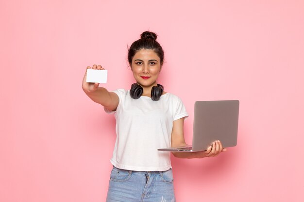 A front view young female in white t-shirt and blue jeans using a laptop with smile