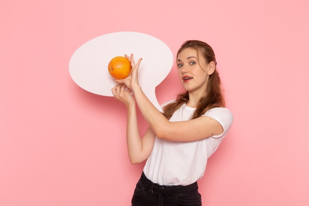 Free photo front view of young female in white t-shirt holding grapefruit and white sign