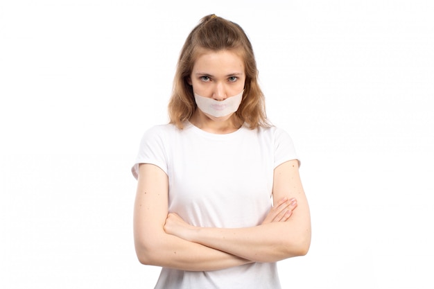 Free photo a front view young female in white t-shirt with white bandage around her mouth displeased afraid on the white