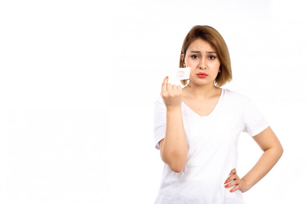 A front view young female in white t-shirt with white bandage around her mouth taking off on the white