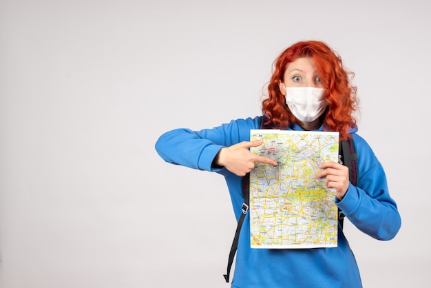 Free photo front view of young female with backpack and map in mask on white wall