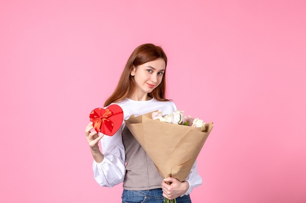 Free Photo front view young female with flowers and present as womens day gift on pink background horizontal march equality love sensual date rose woman