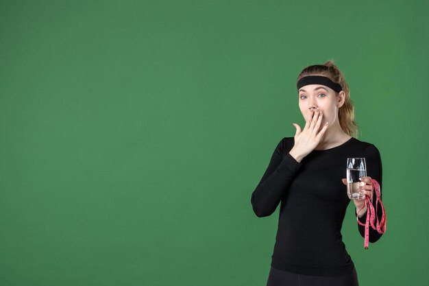 Front view young female with glass of water and waist measure on green background color health body black woman athlete sport