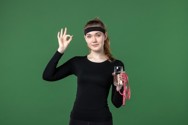 Free photo front view young female with glass of water and waist measure on green