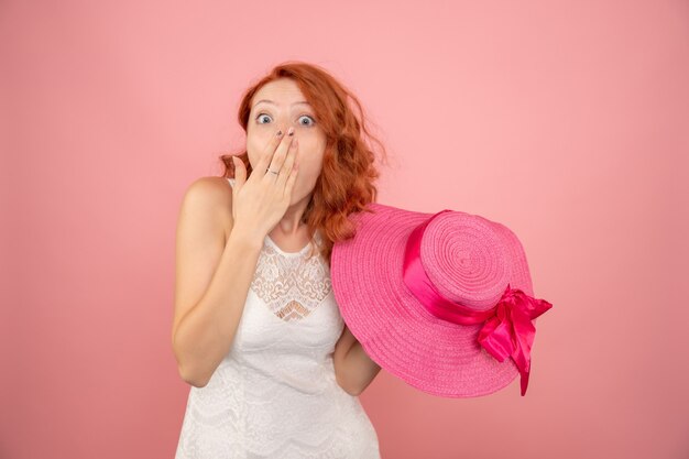 Front view of young female with her pink hat on the pink wall