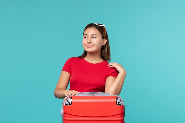 Front view young female with red bag getting ready for vacation on light-blue space